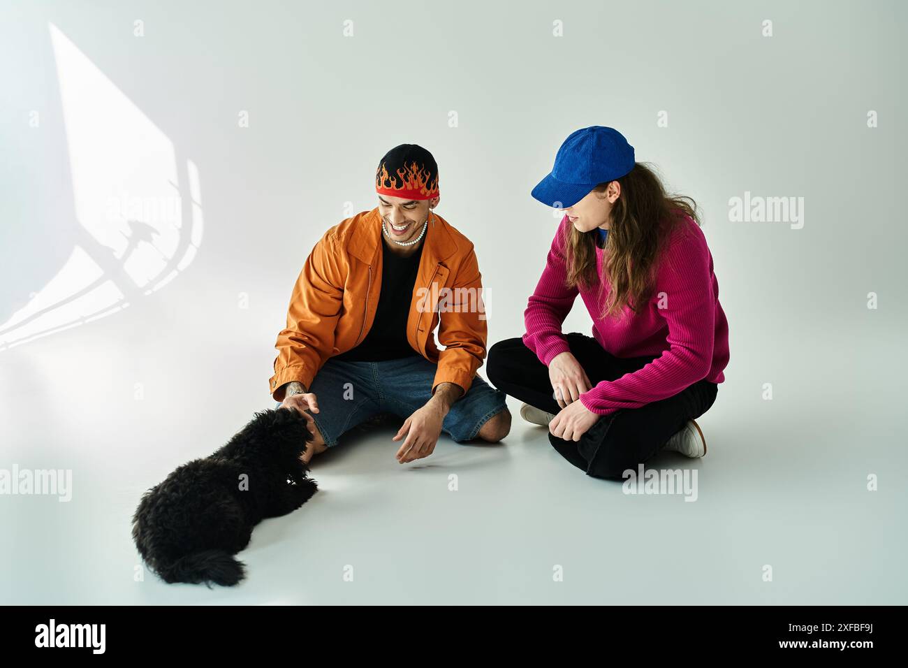two men sit beside a black dog, sharing a peaceful moment. Stock Photo