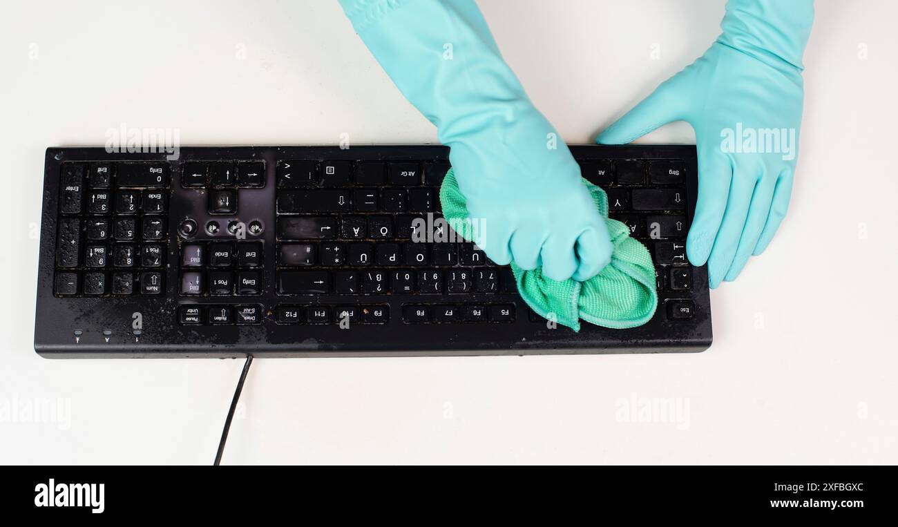Cleaning computer keyboard in office with a wet wipe rag, dusty and ...