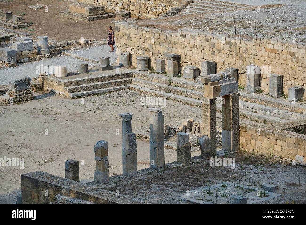 Ruins of an ancient temple with stone columns and a visitor near stone ...