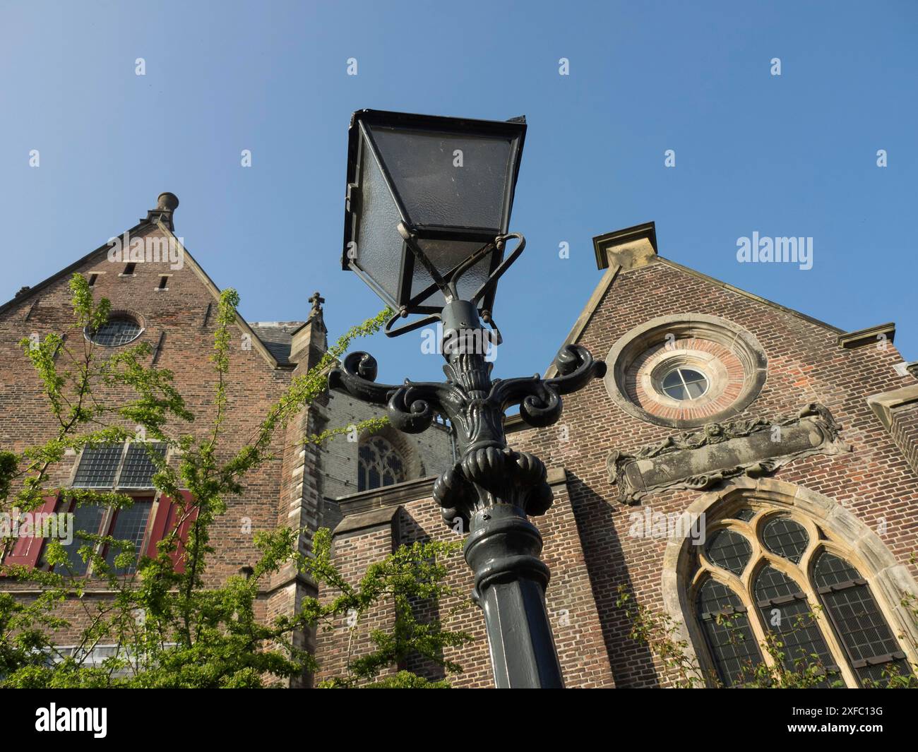 Black street lamp in front of a historic brick building with pointed ...