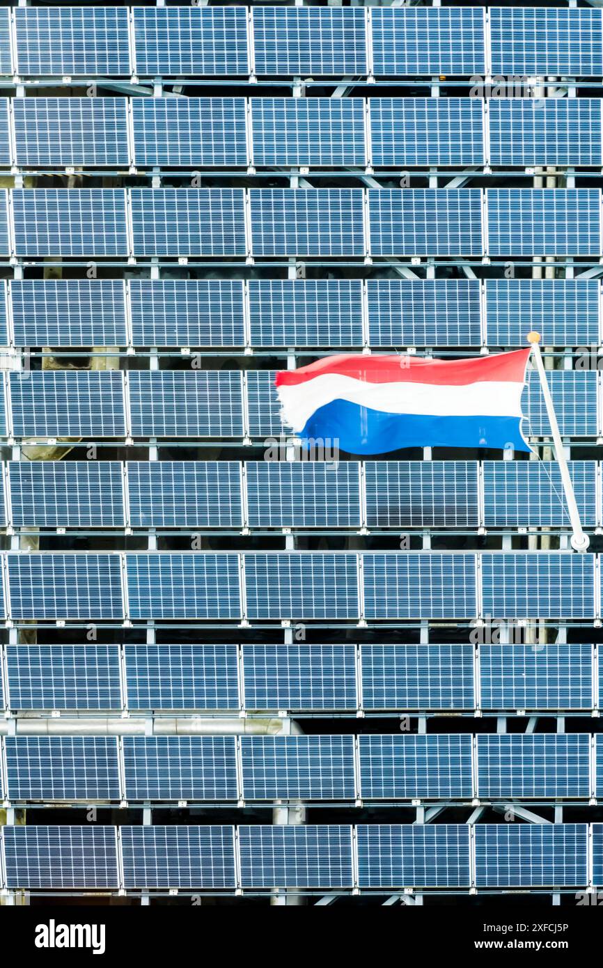 The Dutch flag flying over an array of solar panels or PV cells. Stock Photo