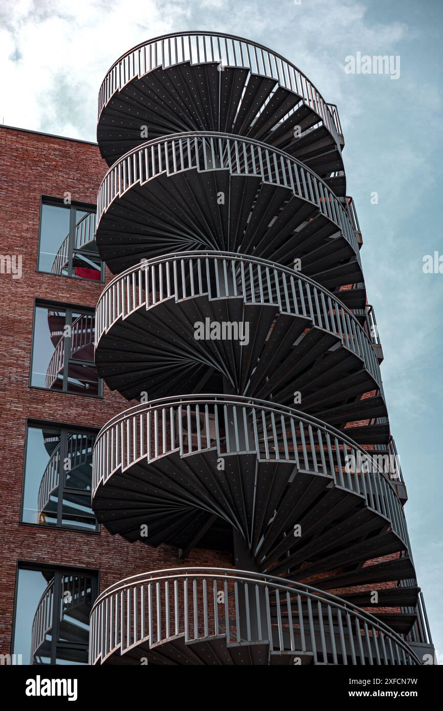 Spiral, wide and modern fire escape stairway of a brick covered ...