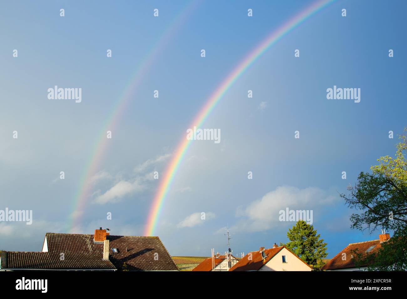 Beautiful rainbow over the house after a storm with clouds in the city ...