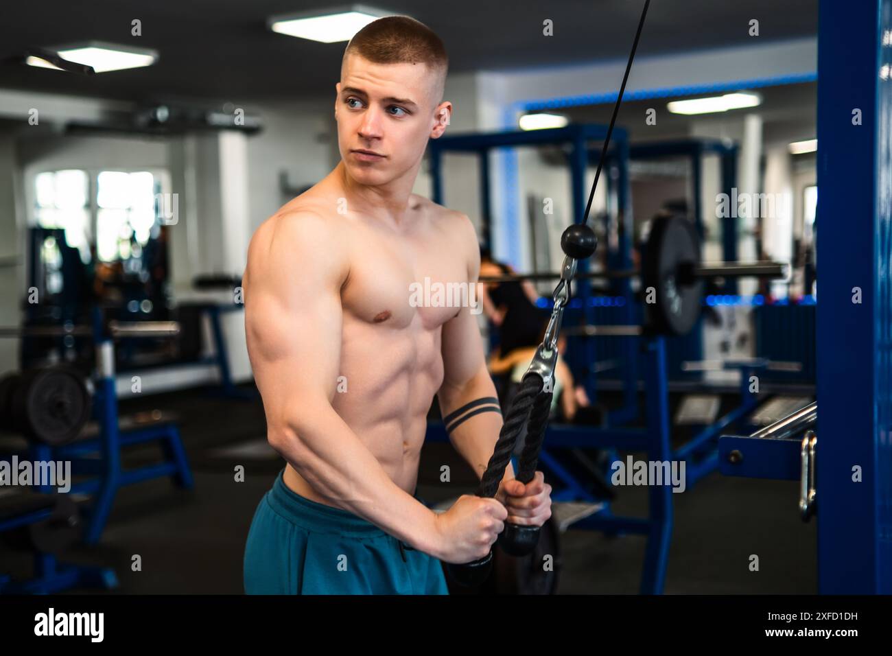 A young man works out on a cable machine in a gym Stock Photo