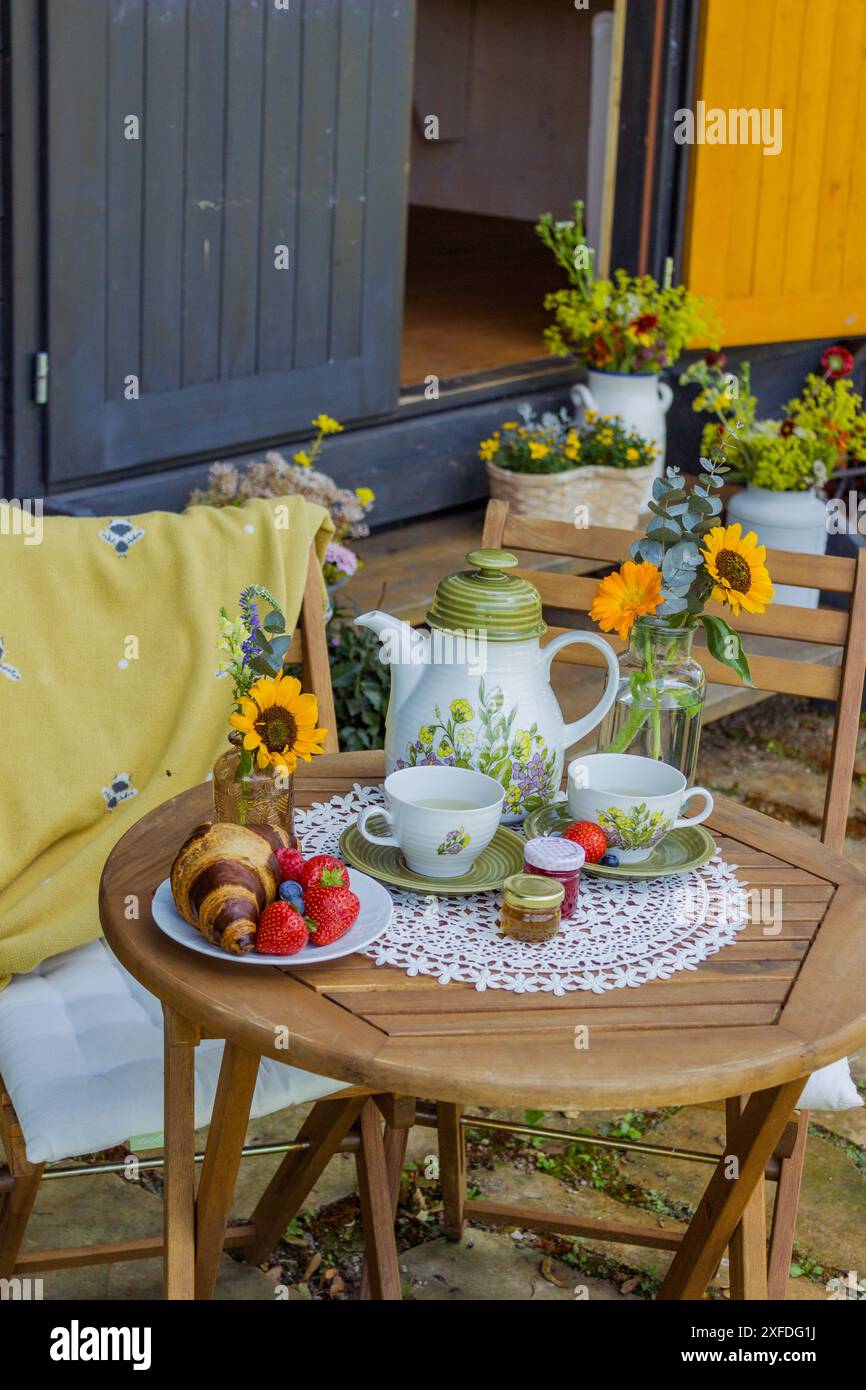 Morning summer tea with flowers and fruits on the veranda in the ...