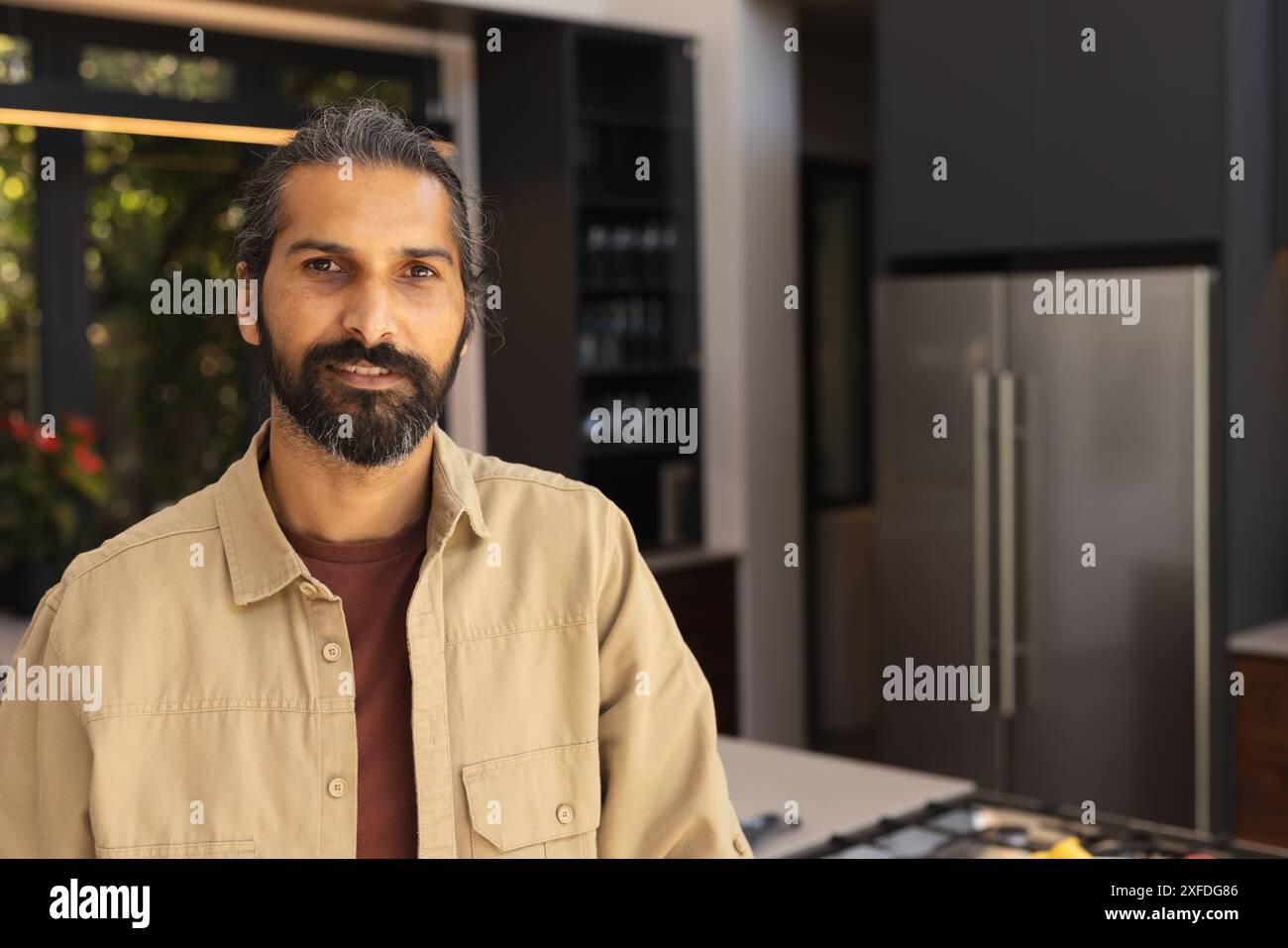 Man standing in modern kitchen, looking at camera, casual attire Stock Photo