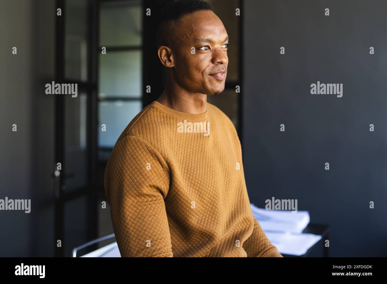 Smiling businessman in casual attire sitting in modern office setting Stock Photo