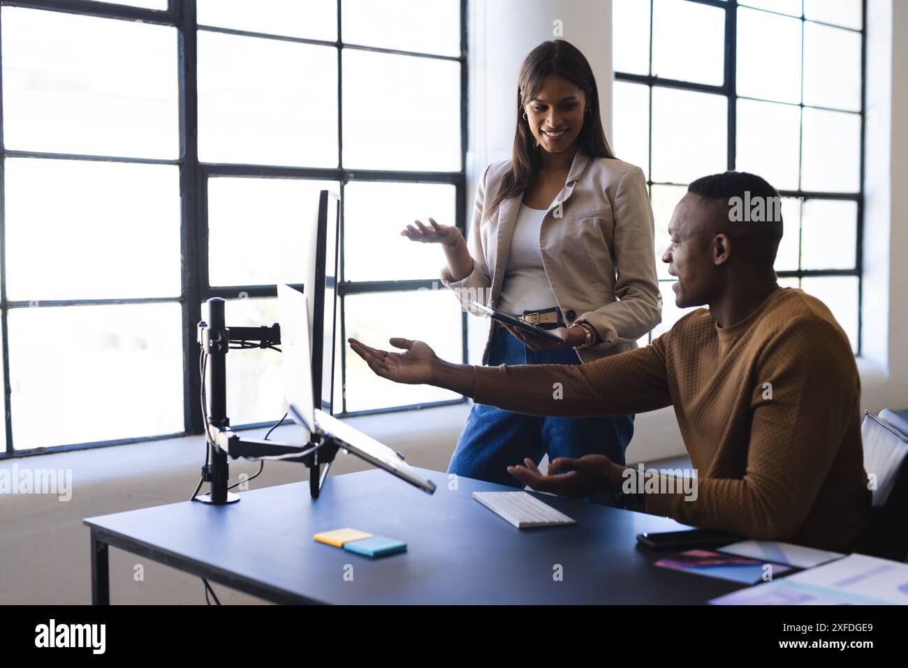 Collaborating on project, colleagues discussing work at computer in modern office Stock Photo