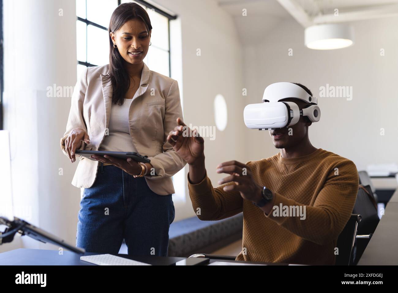 Using VR headset, man interacting while woman holding tablet in office Stock Photo