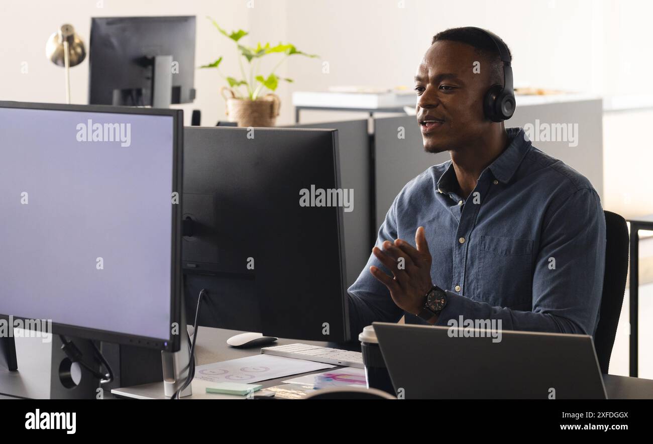 Using headset, man in office working on computer and having video call, copy space Stock Photo