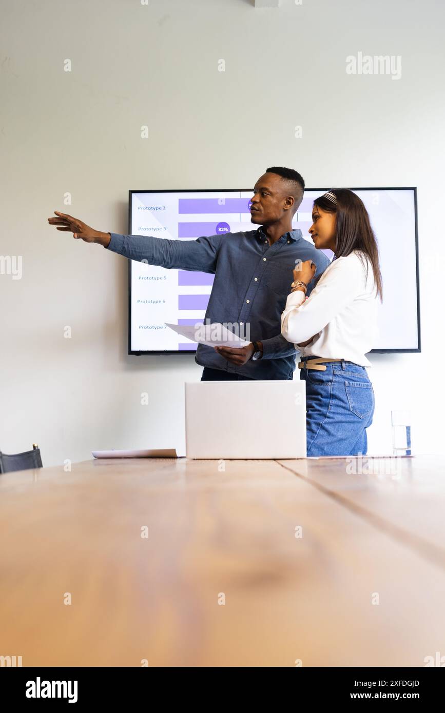 Presenting data on screen, colleagues discussing project in modern office setting, copy space Stock Photo