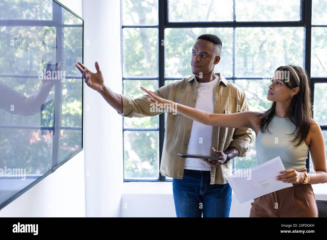 Presenting data on screen, colleagues discussing project in modern office setting, copy space Stock Photo