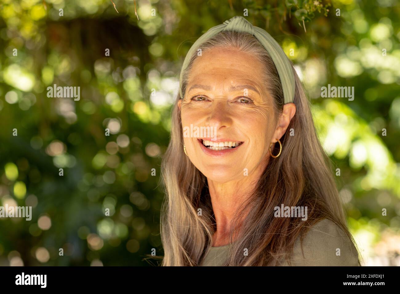 Smiling mature woman with long hair and headband enjoying outdoor nature Stock Photo