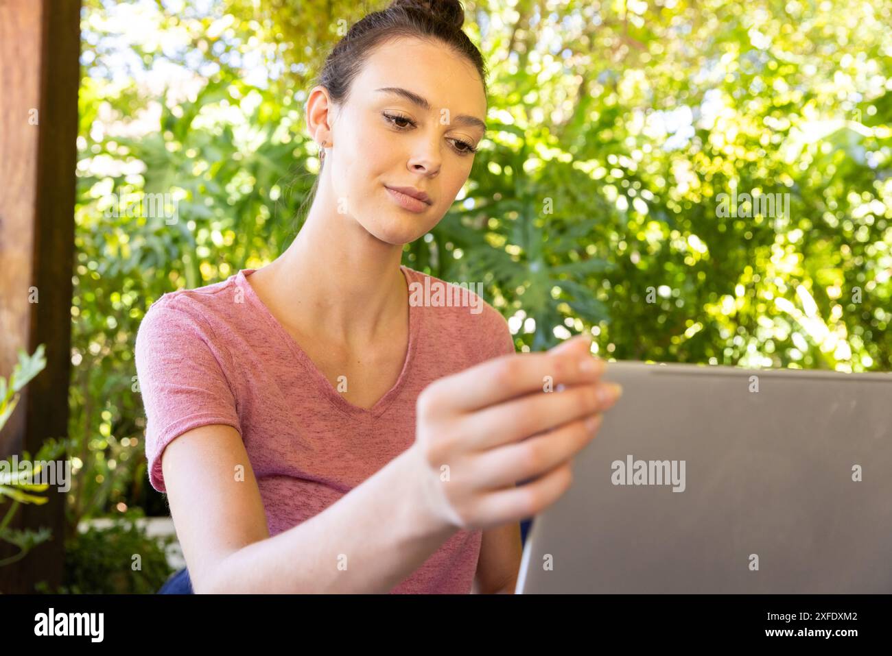 Using laptop, young woman working from home in outdoor setting Stock Photo