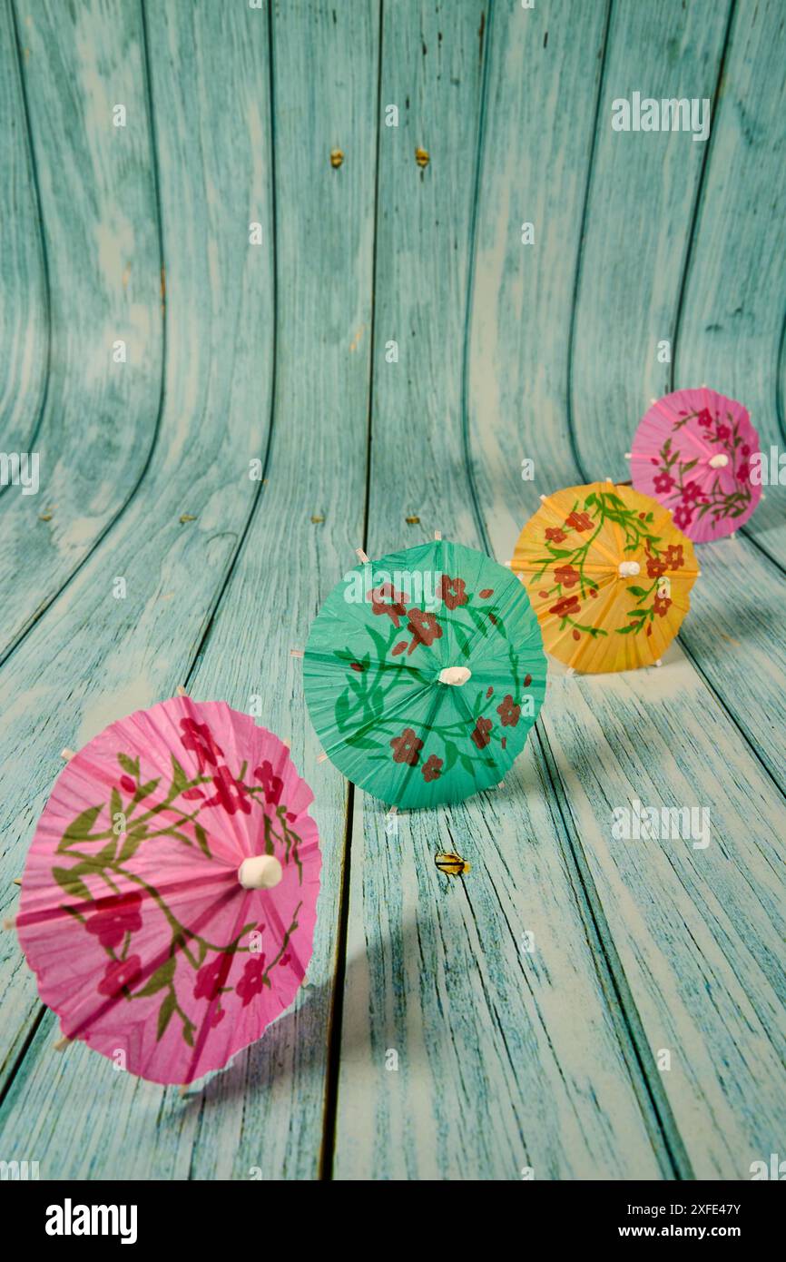 Multicolor cocktail umbrella with floral motifs lined on wood. Stock Photo