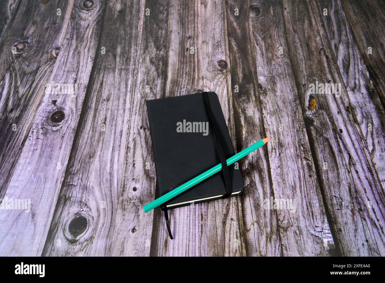 Black notebook with green pen on a wooden table.  Stock Photo