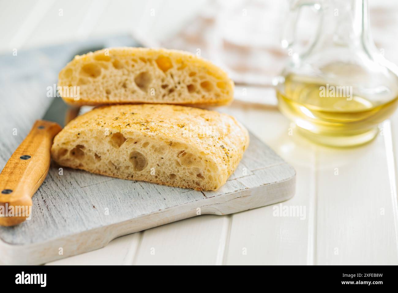Italian ciabatta bread on cutting board on a white table. Stock Photo