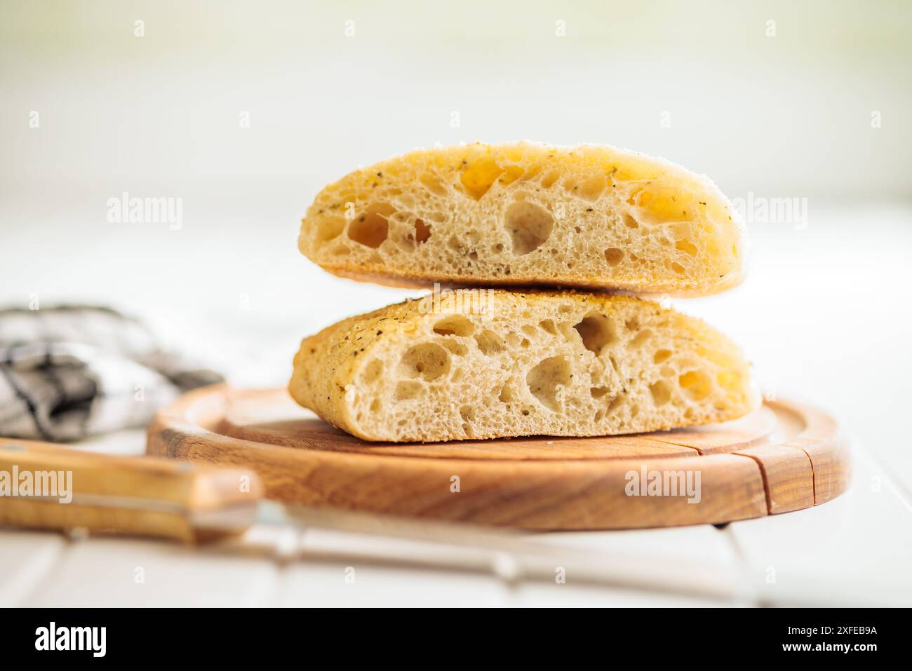 Italian ciabatta bread on cutting board on a white table. Stock Photo