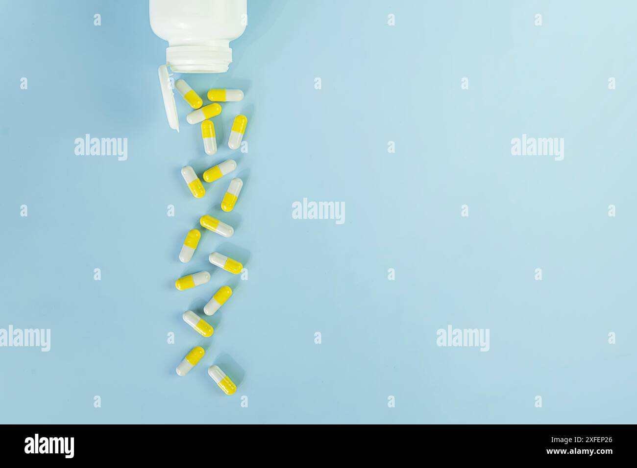 Top view of white bottle with the yellow pills on the blue background. Copy space. Stock Photo