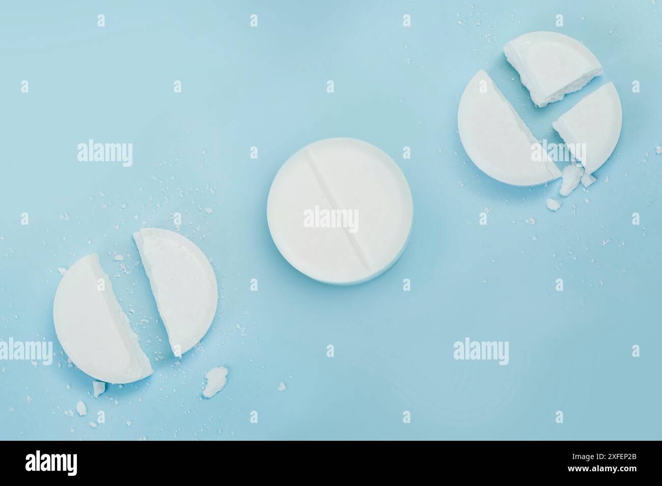 White broken pills lie on a blue background. round tablet was divided equally Stock Photo