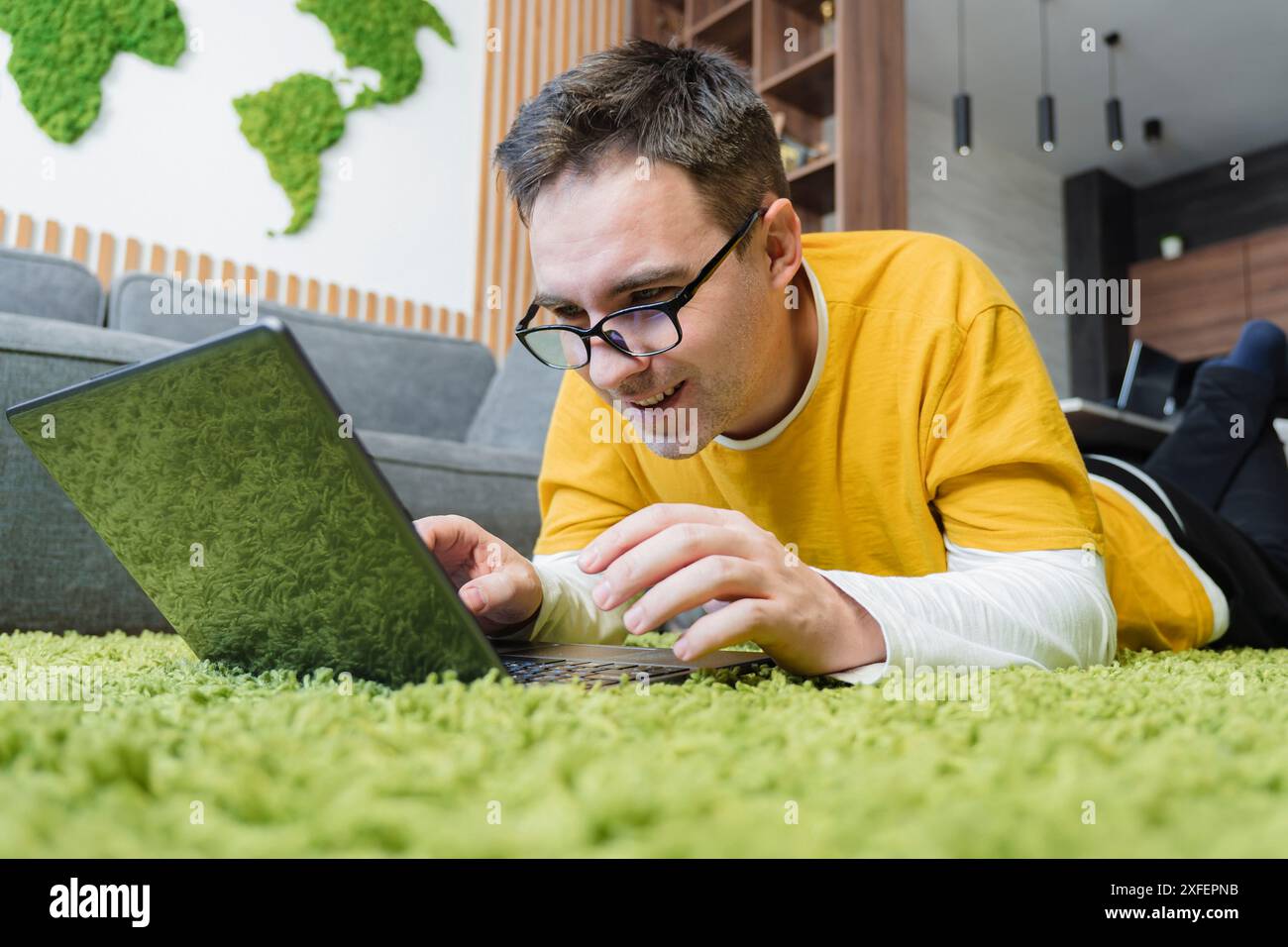 relaxed young man using a laptop on the floor at home. Stock Photo