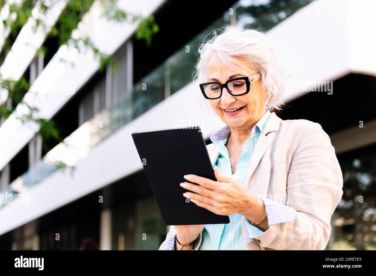 mature woman smiling while using digital tablet Stock Photo