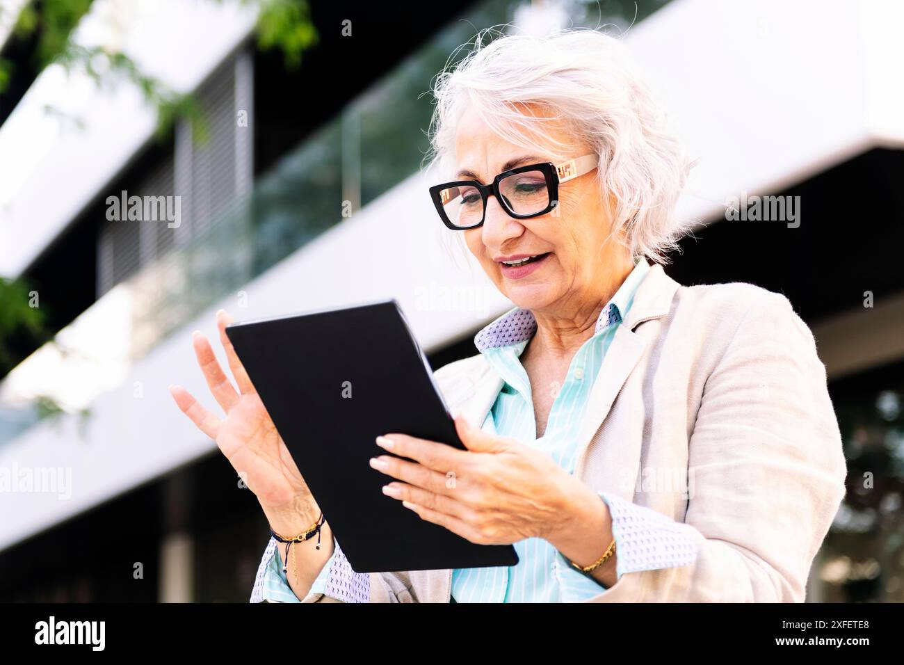 mature woman smiling while using digital tablet Stock Photo