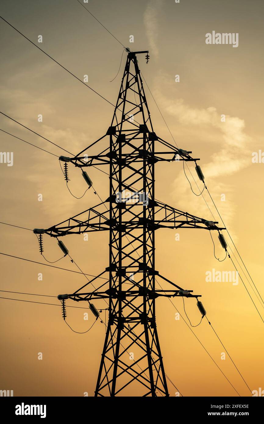 High voltage pylons and power lines against orange sunrise Stock Photo ...