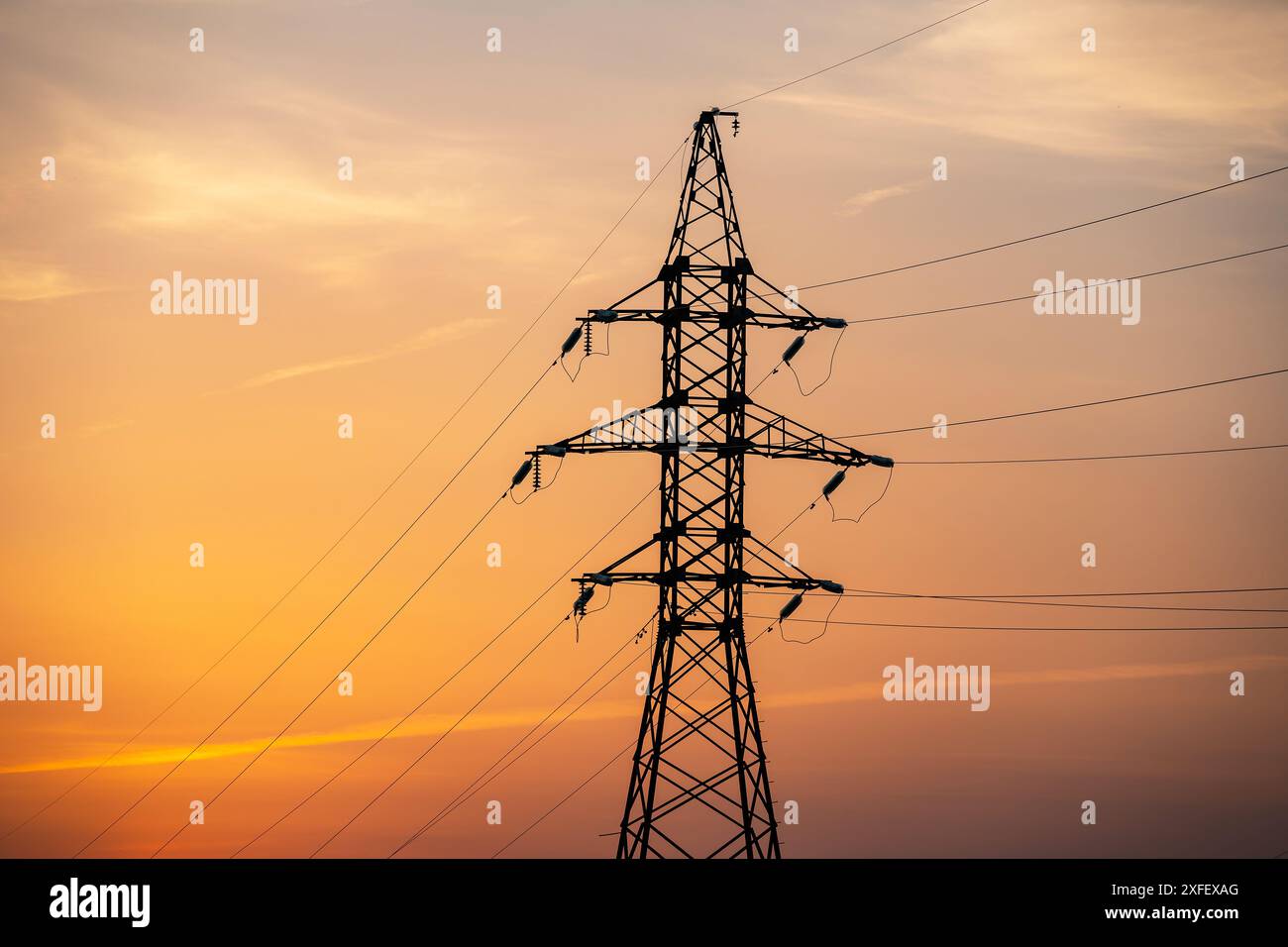 High voltage pylons and power lines against orange sunrise Stock Photo ...