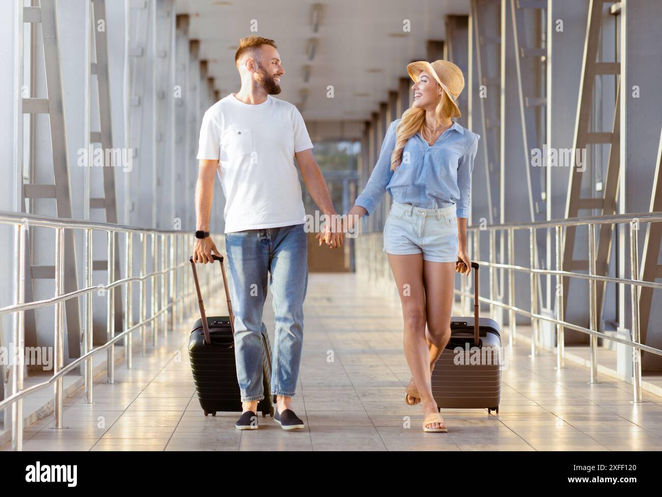 Couple holding hands, walking at covered passage in airport Stock Photo ...