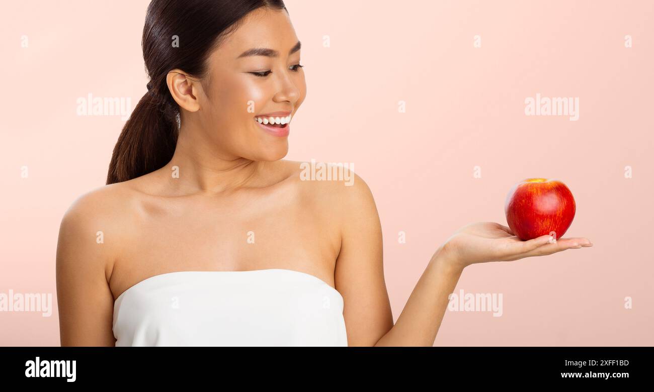 Young Woman Holding Red Apple in White Tank Top Stock Photo