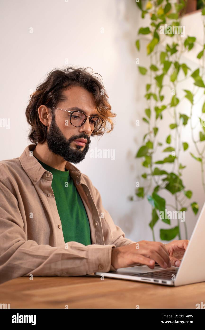 Cheerful male writer working on a novel on his laptop at home. Stock Photo