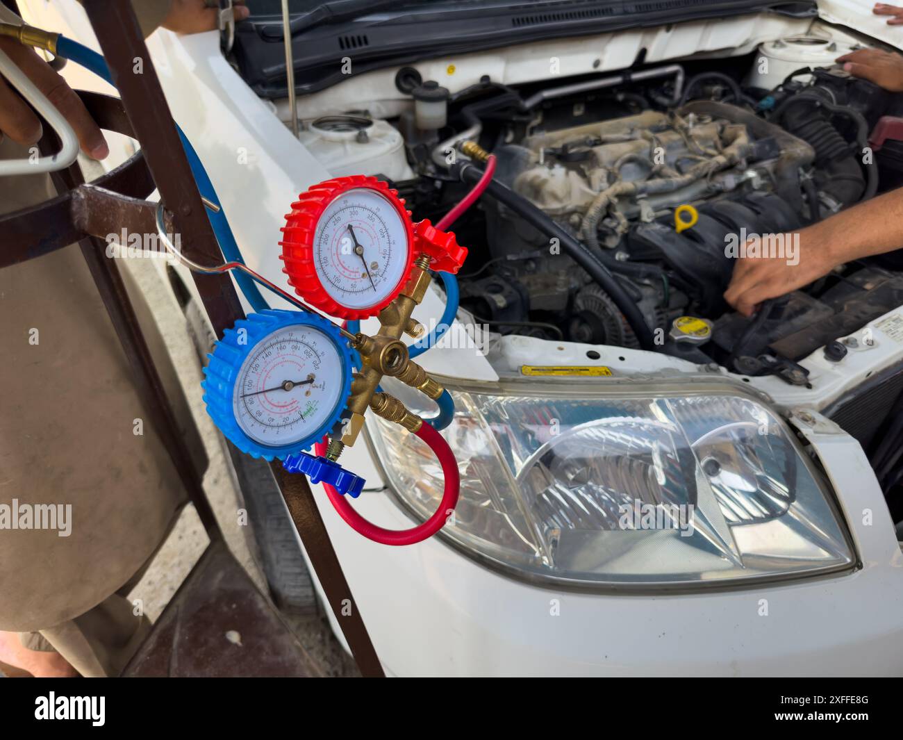 Mechanic Checking Automotive AC Pressure Gauges with Tools Stock Photo
