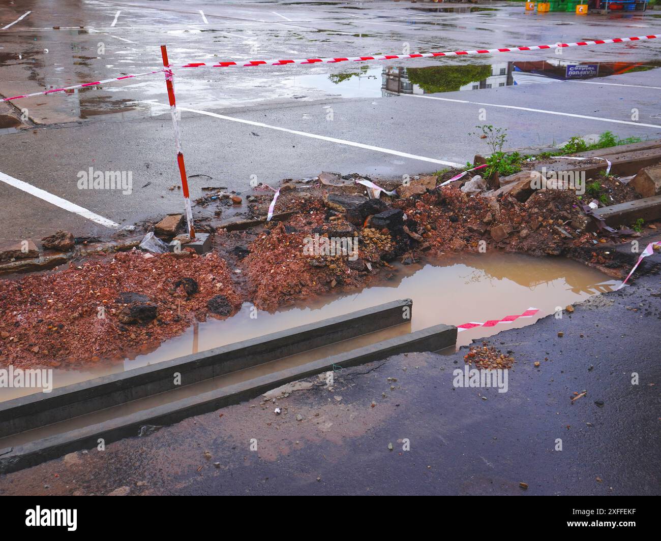 Close-up of road being excavated for renovation, repair of main city road, road construction, pothole during rainy season. Stock Photo