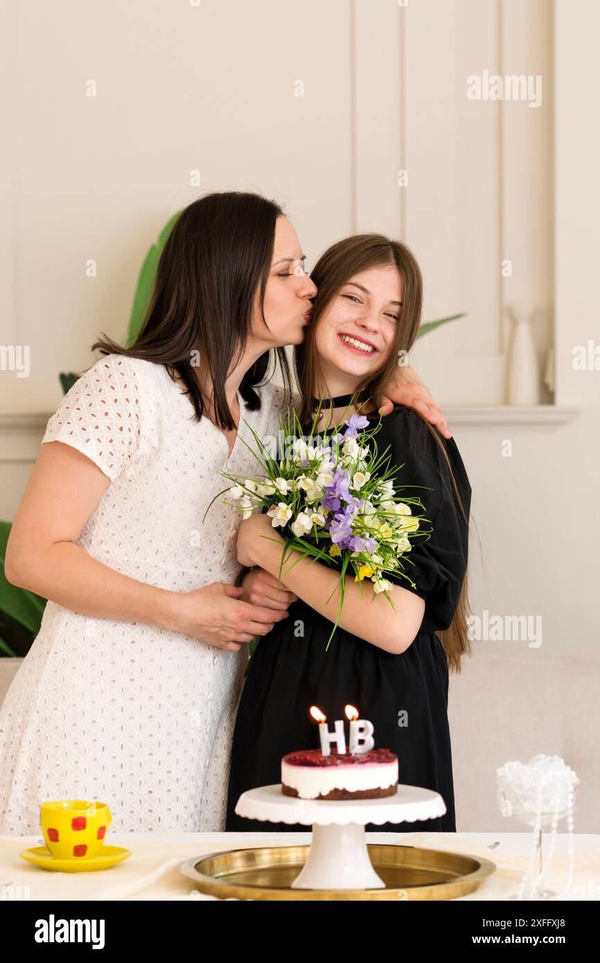 mother-kissing-daughter-at-birthday-celebration-with-cake-portrait-of