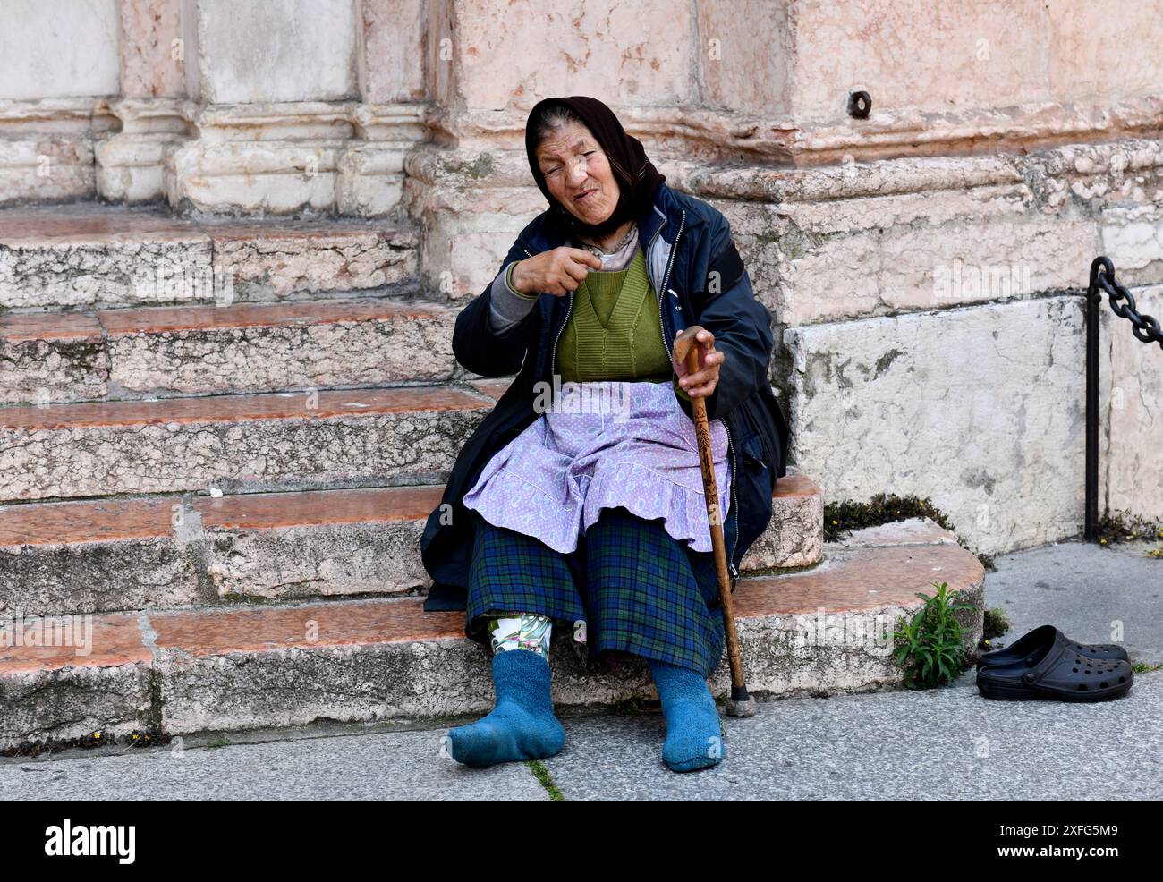 Old lady begging outside Parma Cathedral, Parma, Emilia-Romagna, Italy Stock Photo