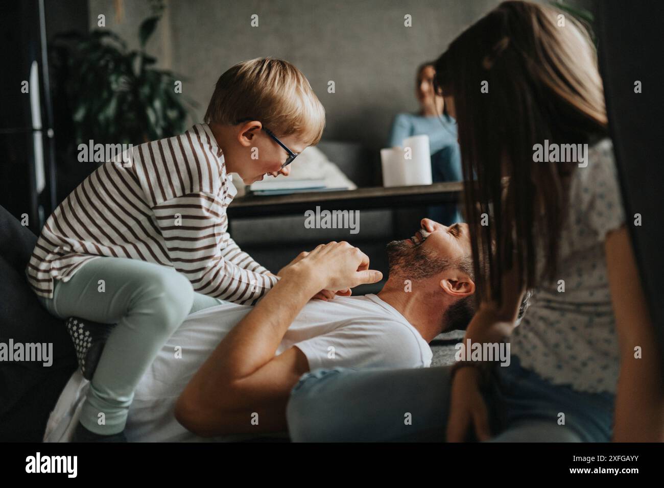 Happy father playing with son while lying down on floor at home Stock Photo