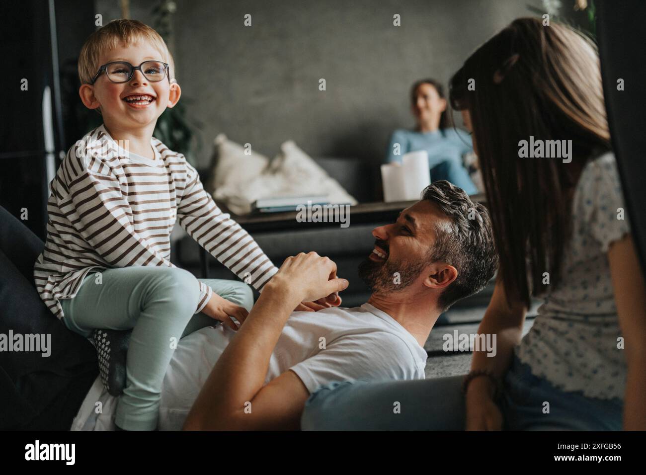 Cheerful children having fun with father lying down on floor at home Stock Photo