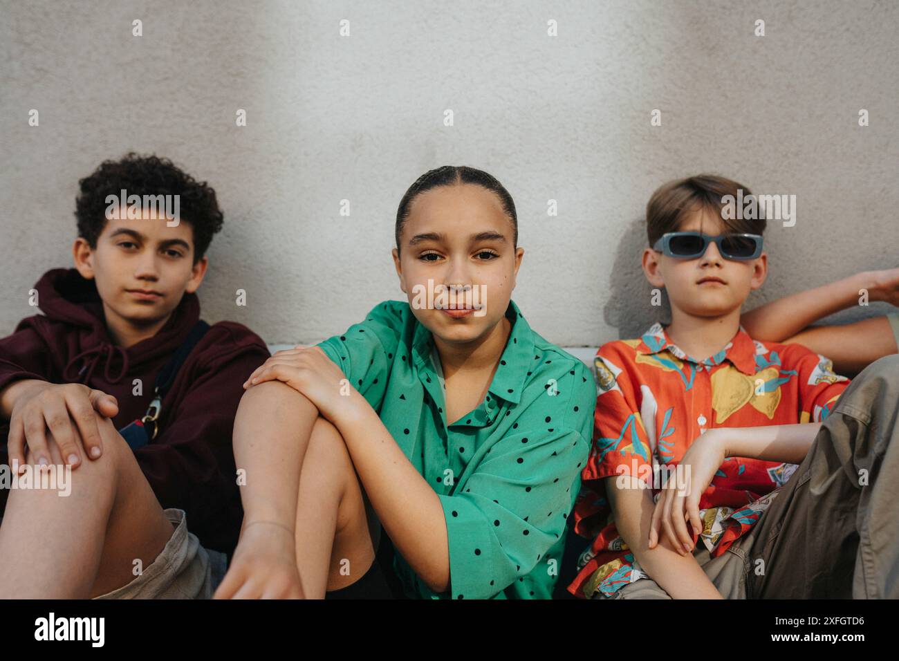 Portrait of girl sitting with boys against wall Stock Photo - Alamy