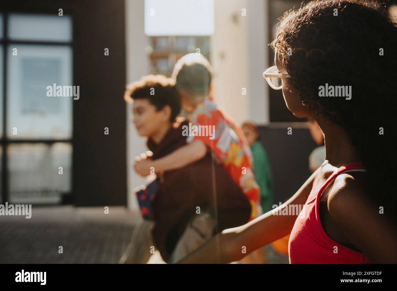 Girl walking with boy piggybacking friend at street Stock Photo