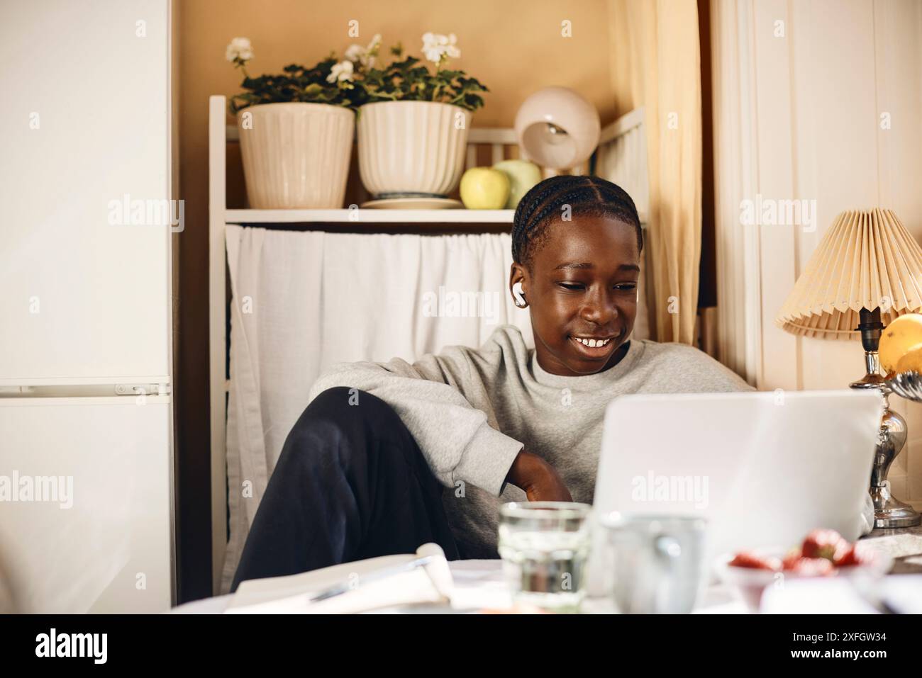 Smiling teenage boy using laptop while sitting at home Stock Photo - Alamy