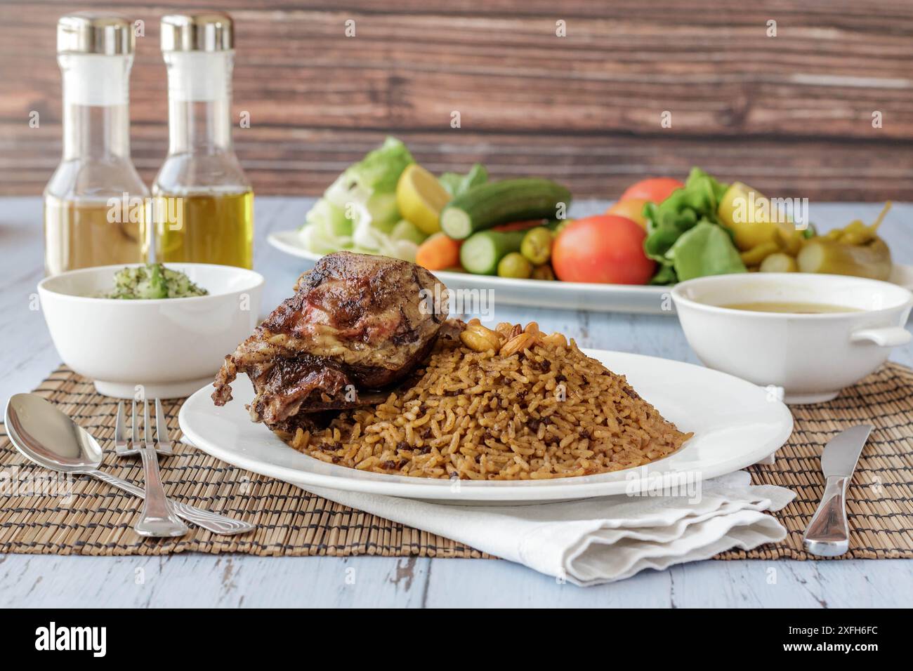 A delicious plate of rice and roasted meat served with vegetables and condiments on a wooden table Stock Photo