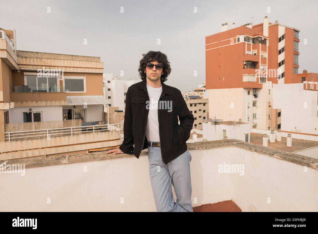 Fashionable young man posing near wall on rooftop Stock Photo