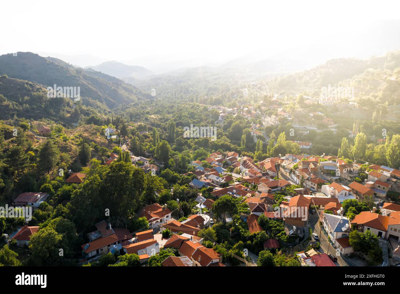 Aerial view of a village bathed in warm sunlight, nestled in a valley ...
