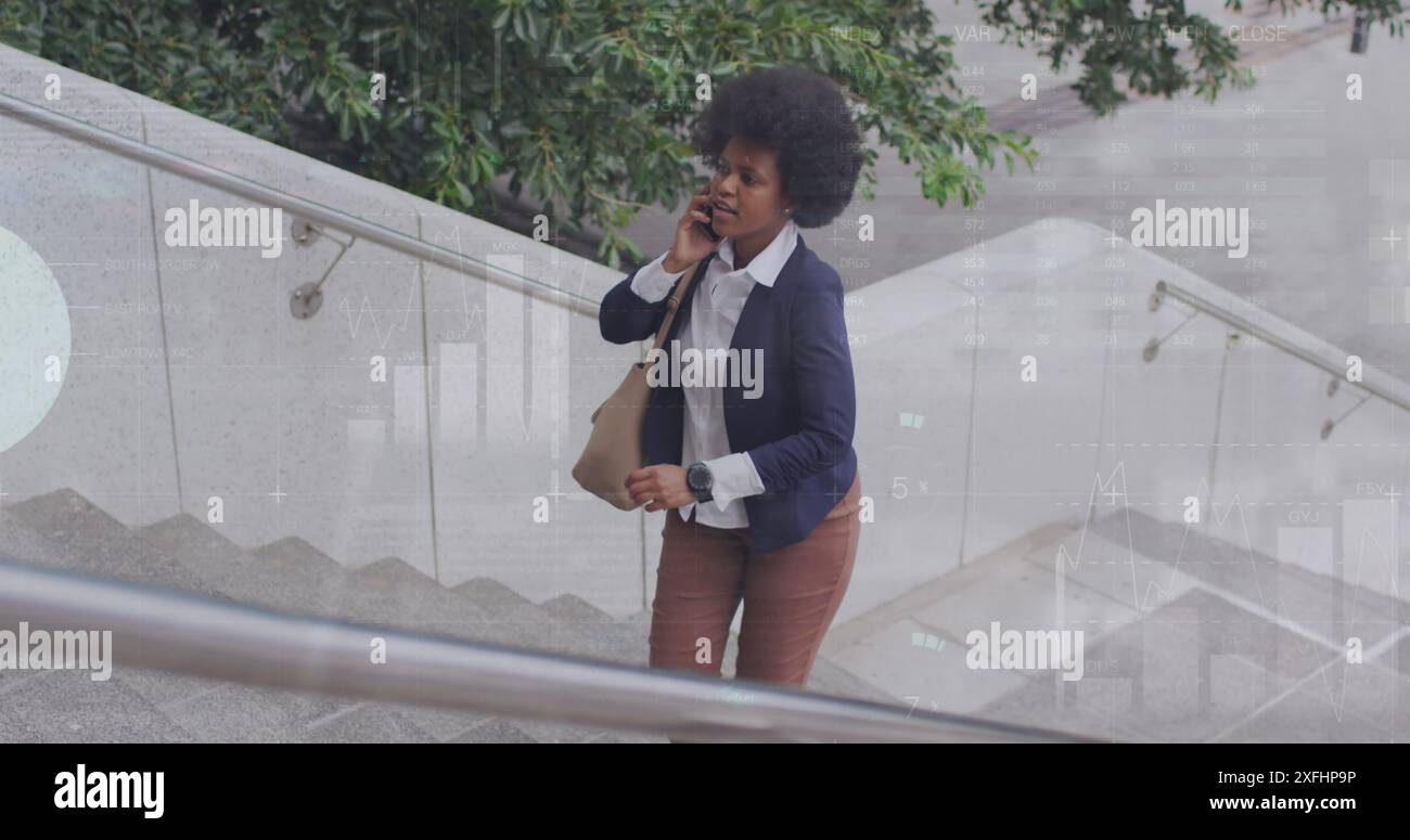 Image of african american woman talking on phone and looking at watch while walking up stairs Stock Photo