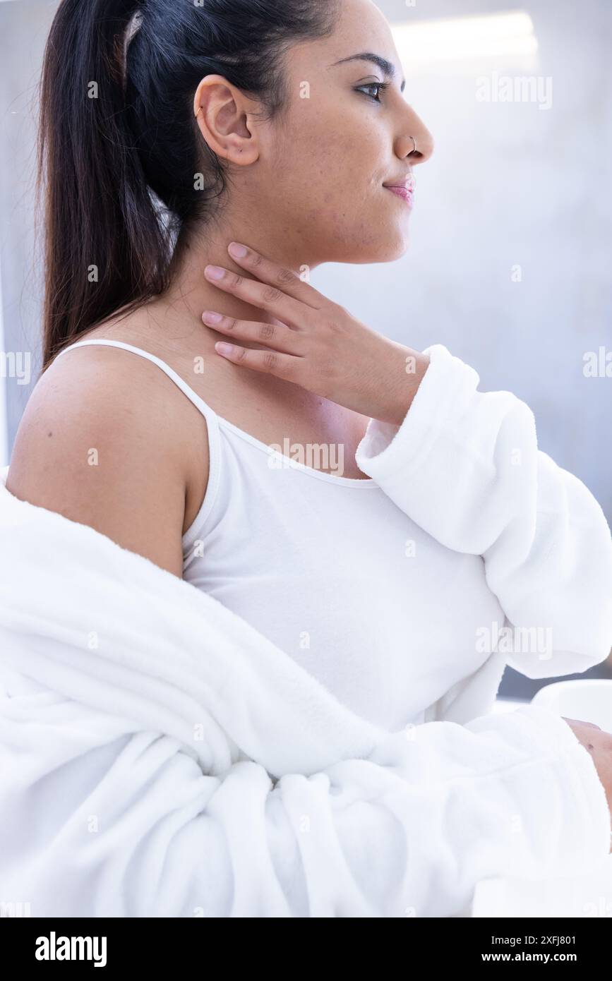 Relaxing at spa, woman in white robe touching her neck Stock Photo - Alamy