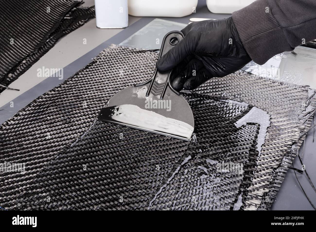 hand working epoxy resin into woven carbon fiber reinforcement cloth