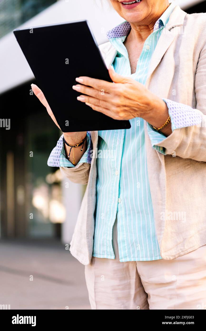 mature woman smiling while using digital tablet Stock Photo