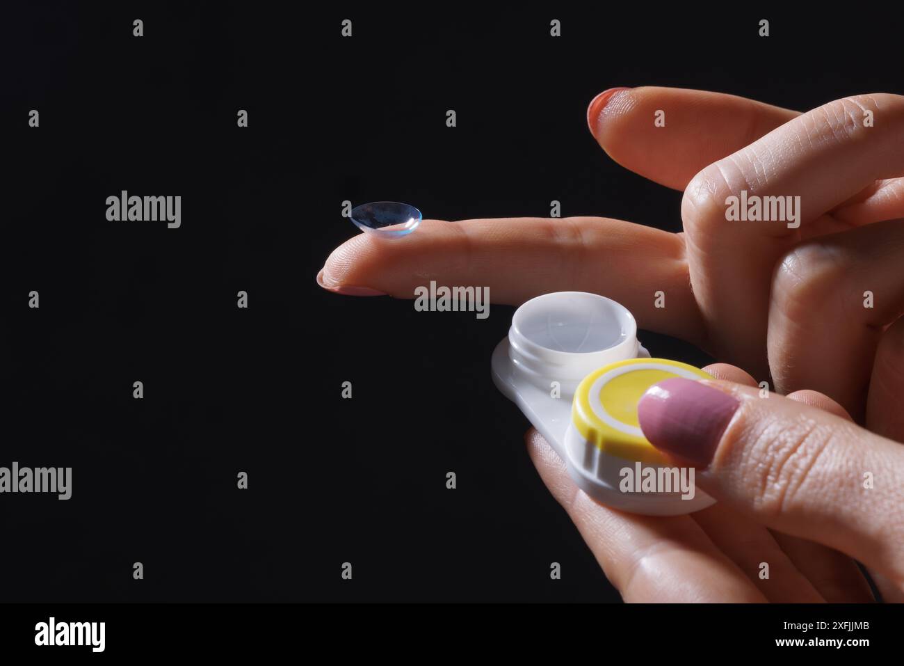 woman puts on contact lenses for vision close-up on a dark background, macro photo of contact lenses, astigmatic eyes, colored lenses Stock Photo