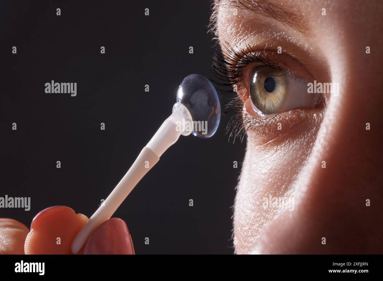 woman puts on contact lenses for vision close-up on a dark background, macro photo of contact lenses, astigmatic eyes, colored lenses Stock Photo